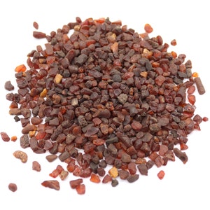 May include: A pile of small, dark red amber stones on a white background.
