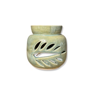 May include: A green ceramic oil diffuser with a leaf design. The diffuser has a small bowl on top for holding oil and a larger bowl underneath for holding water.