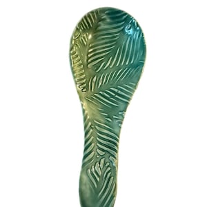 May include: A green and yellow ceramic spoon rest with a leaf pattern.