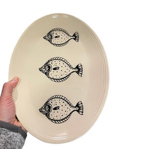 May include: A white oval ceramic serving platter with three black and white fish illustrations.