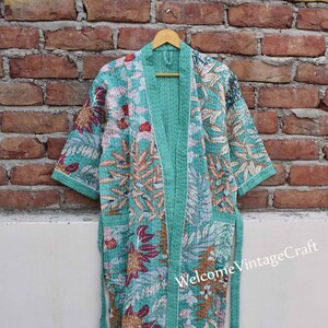 May include: A teal blue quilted robe with a floral print and white trim. The robe has a tie belt and is made of cotton.