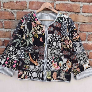 Könnte beinhalten: Eine schwarze gesteppte Jacke mit einem floralen Patchwork-Muster. Die Jacke hat einen runden Ausschnitt und einen Knopfverschluss. Der Stoff ist eine Mischung aus Schwarz, Weiß und Rosa.