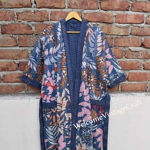 Könnte beinhalten: Eine blaue Robe mit floralem Muster und einem Bindegürtel. Die Robe ist gesteppt und aus Baumwolle.