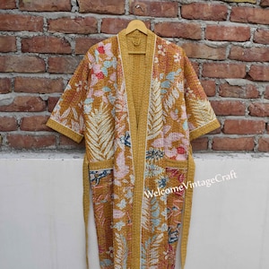 Peut inclure: Une robe de chambre matelassée jaune moutarde à imprimé floral et bordure blanche. La robe a une ceinture à nouer et des manches longues.