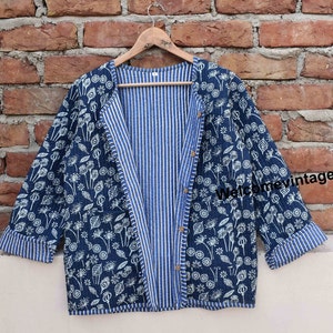 May include: A blue and white cotton jacket with a floral print on one side and a striped pattern on the other. The jacket has a long sleeve and a button closure. The text "Welcome vintagecraft" is visible on the jacket.