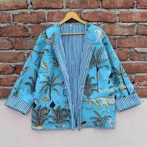 Puede incluir: Una chaqueta acolchada azul y blanca con forro a rayas y estampado de animales de la selva. La chaqueta tiene cierre de botón y mangas largas.