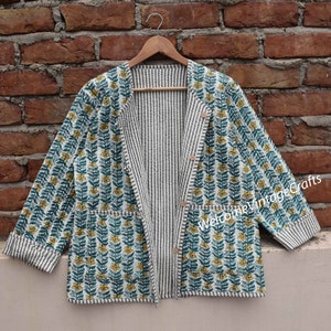 Op de afbeelding: Een wit en blauw bloemenprint jack met een gestreepte voering. Het jack heeft een knoopsluiting en twee zakken. De tekst "Welcome Vintage Crafts" is zichtbaar op het jack.