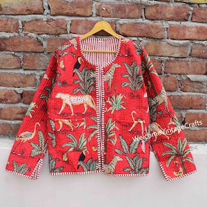 Puede incluir: Chaqueta acolchada roja con cierre de cremallera y forro a rayas blanco y rojo. La chaqueta presenta un estampado de jungla con animales como cebras, leopardos, tucanes y flamencos.