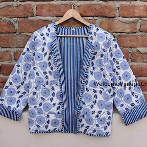 Pode incluir: Uma jaqueta com padrão floral branco e azul com forro listrado azul e branco. A jaqueta tem fecho de botão e mangas compridas.