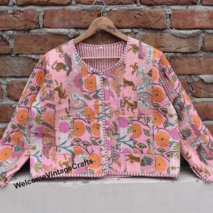 Puede incluir: Una chaqueta acolchada rosa con estampado floral y de tigre. La chaqueta tiene cierre de botón y cuello en V. El texto "WelcomeVintageCrafts" es visible en la parte inferior de la chaqueta.