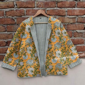 May include: A yellow and green floral print quilted jacket with a striped lining. The jacket has a long sleeve and a relaxed fit. The text "WelcomeVintageCrafts" is visible on the bottom right corner of the jacket.