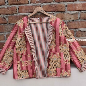 Könnte beinhalten: Eine rosafarbene und braune gesteppte Jacke mit Tigermuster und gestreiftem Futter. Die Jacke hat einen Kragen und lange Ärmel. WelcomeVintageCrafts ist in der unteren rechten Ecke des Bildes gedruckt.