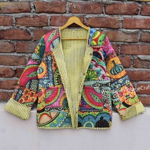 Könnte beinhalten: Eine bunte Patchwork-Steppjacke mit gelbem und weißem gestreiftem Futter. Die Jacke hat einen vorderen Verschluss und lange Ärmel. Der Stoff zeigt eine Vielzahl von Mustern, darunter florale, geometrische und Paisley-Muster. Der Text "Welcome VintageCrafts" ist auf der rechten Seite der Jacke sichtbar.