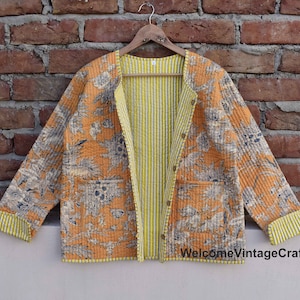 Peut inclure: Une veste matelassée à imprimé floral dans les tons orange et marron. La veste est doublée de rayures jaunes et noires et bordée de jaune. Le texte "WelcomeVintageCrafts" est visible dans le coin inférieur droit de l'image.