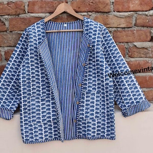 Puede incluir: Una chaqueta de algodón azul y blanco con forro a rayas. La chaqueta tiene cierre de botón y un ajuste holgado.