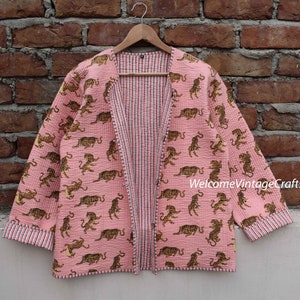 May include: A pink quilted jacket with a tiger print and a striped lining. The jacket has a long sleeve and a front opening. The text "WelcomeVintageCrafts" is visible on the bottom right corner of the image.