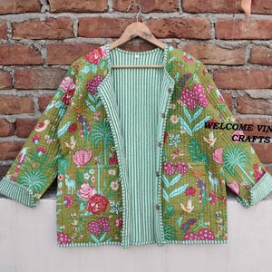 May include: A green quilted jacket with a floral print and a striped lining. The jacket has a button closure and two pockets. The text "WELCOME VINTAGE CRAFTS" is visible on the jacket.