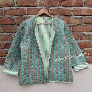 Puede incluir: Una chaqueta acolchada azul turquesa con estampado floral y forro a rayas verde y blanco. La chaqueta tiene cierre de botón y mangas largas.