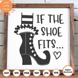 May include: A framed, black and white graphic featuring a stylized witch's boot with the text "IF THE SHOE FITS..." and a heart symbol. The artwork is set against a white background within a wooden frame.