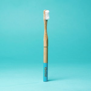 May include: A blue and brown bamboo toothbrush with white bristles. The toothbrush has the word "Oetker" printed on the handle.