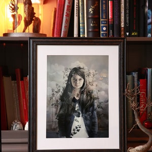 Könnte beinhalten: Ein gerahmter Druck eines Gemäldes, das eine junge Person mit langen dunklen Haaren zeigt, die eine blaue Jacke trägt und vor einem bewölkten Hintergrund mit einem Blumenranken um den Kopf steht.