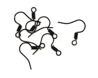 May include: A close-up of a group of black earring hooks with spring closures. The hooks are scattered on a white surface.