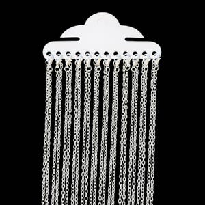 May include: A white plastic display card with 18 silver chains hanging from it.