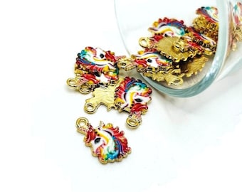 May include: Gold unicorn charms with rainbow manes and tails. The charms are scattered on a white surface, with some spilling from a clear glass container. Each charm has a loop for attaching to jewellery.