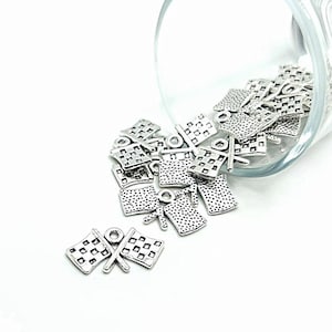 May include: A glass jar filled with silver checkered flag charms. The charms are scattered on a white surface.