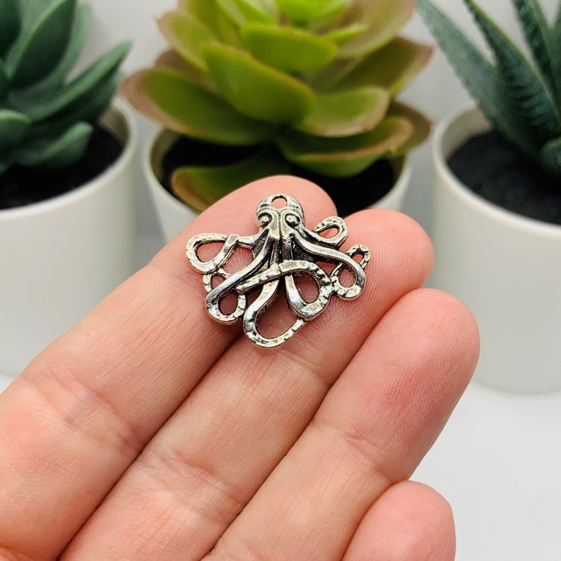 May include: Silver-toned octopus charm with detailed tentacles. The charm is a popular choice for jewelry making, scrapbooking, and other craft projects.