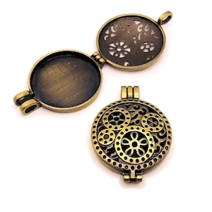 Może przedstawiać: Złoty medalion z klapką na zawiasach. Medalion ma ozdobny, ażurowy wzór z motywem kwiatowym. Medalion jest zamknięty na pierwszym zdjęciu i otwarty na drugim zdjęciu.