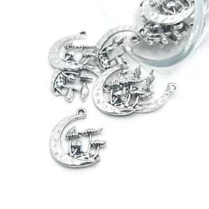 May include: Silver charm pendants in the shape of a crescent moon with a cluster of mushrooms in the center.