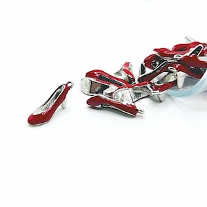 May include: A group of red metal shoe charms with silver accents. The charms are in the shape of high-heeled shoes.