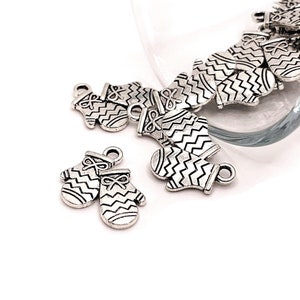 May include: Silver-toned metal charms shaped like mittens with a zig-zag pattern. The charms have a loop at the top for attaching to jewelry or other crafts.
