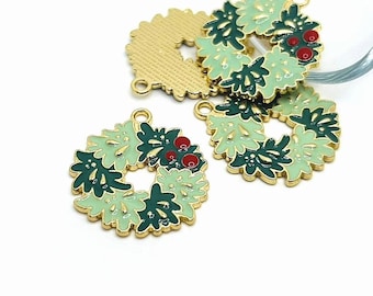 May include: Close-up of several Christmas wreath charms. The charms are gold-colored metal with a wreath design in shades of green and red berries. The wreaths have a loop at the top for attaching to jewelry or other crafts.