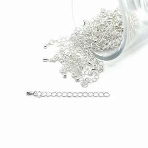 May include: A pile of silver chain links in a glass jar, with a separate short length of chain on a white background.