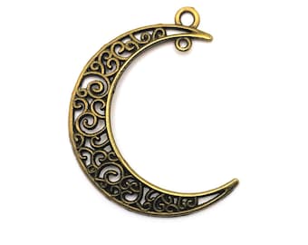 May include: A gold-toned metal crescent moon charm with a filigree design. The charm has a loop at the top for attaching to jewelry or other crafts.