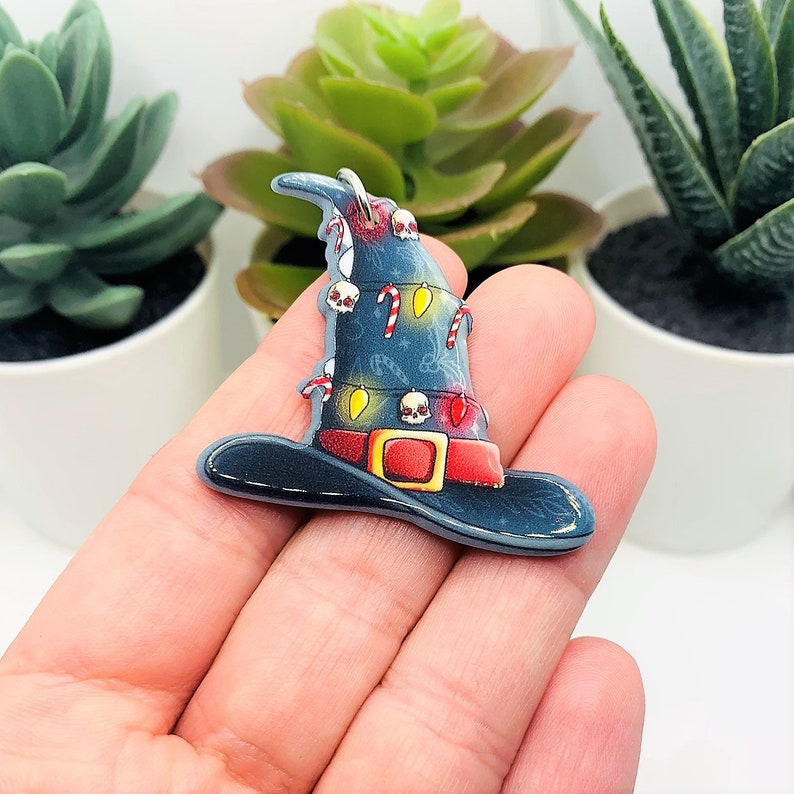 May include: A blue witch's hat with a white and red candy cane design and yellow and red lights. The hat has a black brim and a silver loop at the top.