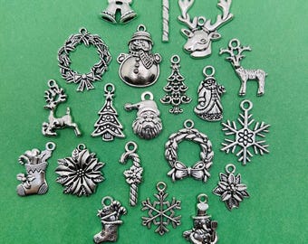 May include: A collection of silver-colored Christmas charms, including snowflakes, reindeer, snowmen, Santa Claus, Christmas trees, wreaths, bells, and candy canes. These charms are designed with intricate details and are perfect for holiday-themed jewelry or craft projects.