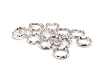 May include: A pile of silver jump rings, a type of jewelry finding used for connecting chains, cords, and other jewelry components.