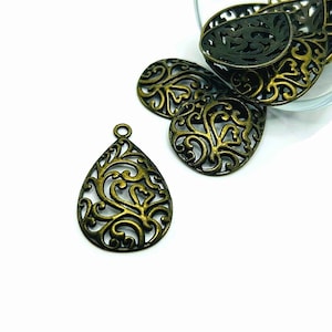 May include: A set of gold-toned metal filigree teardrop charms with intricate floral designs. The charms are perfect for jewelry making, scrapbooking, and other craft projects.