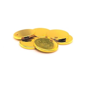 May include: A group of six gold-colored metal round discs with a small hole in the center. The discs are stacked on top of each other.