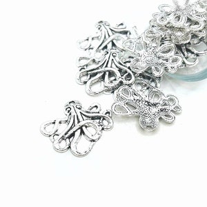 May include: Silver metal octopus charms with intricate details. The charms are scattered on a white surface.