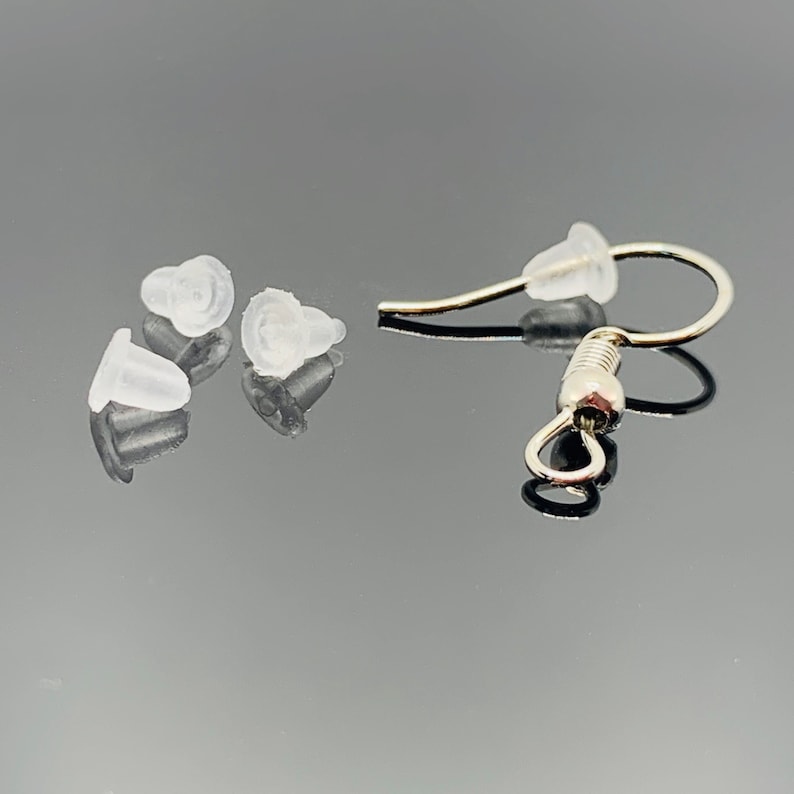 Puede incluir: Cuatro tapones de silicona transparentes para pendientes y un gancho de pendiente plateado con cierre de resorte.