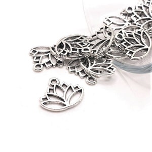 Könnte beinhalten: Ein Haufen silberfarbener Metall-Lotosblüten-Anhänger mit einem Loch oben zum Anbringen an Schmuck oder anderen Bastelarbeiten.
