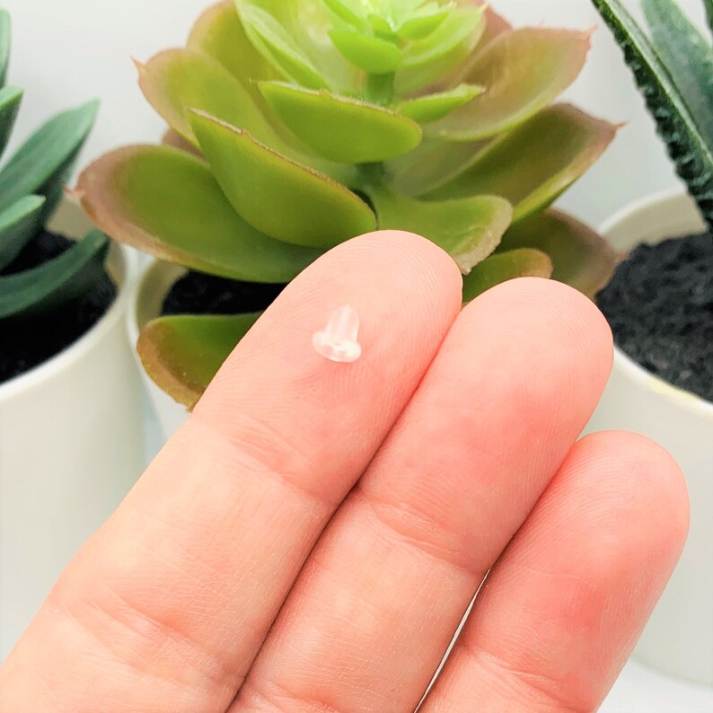 Puede incluir: Una punta de auricular de silicona transparente. La punta es peque&ntilde;a y redonda, con un agujero en el centro. La punta est&aacute; apoyada en un dedo.