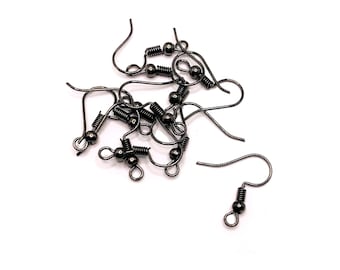 May include: A close-up of a pile of black earring hooks with spring closures. The hooks are made of metal and have a shiny finish.