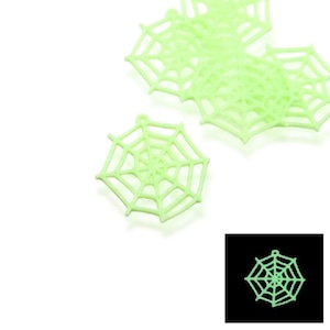 May include: Several light green spiderweb charms with a small loop at the top for hanging. The spiderwebs are a pale green color and are set against a white background. A small, glowing spiderweb is in the bottom right corner.