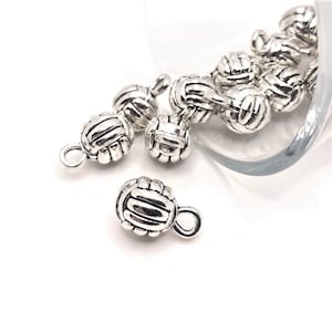 Pode incluir: Encantos de voleibol prateados com um laço para prender em joias ou artesanato.