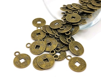 May include: A pile of antique gold-colored Chinese coins with a square hole in the center and Chinese characters on the surface. The coins have a loop attached to the top for hanging or attaching to a chain.